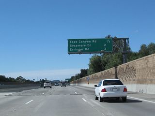 This mileage sign along California 118 (Ronald Reagan Freeway) west provides the distance to the next three exits: Exit 27, Tapo Canyon Road; Exit 25, Sycamore Drive; and Exit 24, Erringer Road. The mileage sign was moved from the median to the right to accommodate freeway expansion (carpool/HOV lane).