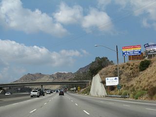 A California 118 west reassurance shield is posted after the California 27 on-ramp. From here, the freeway travels uphill to the Santa Susana Pass.