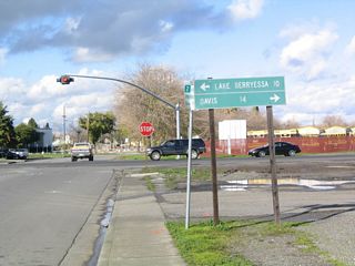 SR 128 travels west from Railroad Avenue in Winters ten miles to Lake Berryessa. Davis lies 14 miles to the east via SR 128 (Grant Avenue) and Yolo County Route E-6 (Russell Boulevard) from Winters. This distance sign was barely legible as of 2024.