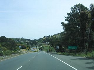 Now approaching Reed Ranch Road (no traffic signal), the speed limit decreases and the brief expressway segment comes to an end as the right lane ends. An old alignment of Tiburon Boulevard can be explored here; it is located closer to the bayshore and is now known as Greenwood Beach Road; it was bypassed with the expressway opening in 1966.