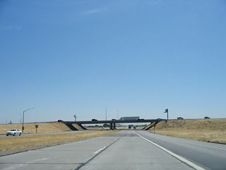 The Interstate 5 cloverleaf interchange comes into view along eastbound California 132. The next ramp is a loop ramp that connects to Interstate 5 north.