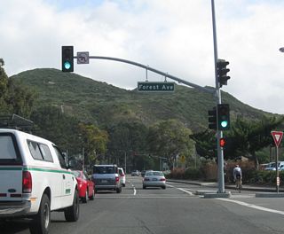 After merging with Cliff Drive, northbound California 133 (Laguna Canyon Road) meets Forest Avenue at this traffic signal. The state route now moves to leave the downtown area of Laguna Beach and proceed into Laguna Canyon, which is part of the city of Laguna Beach.