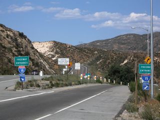 A pair of freeway entrance signs flank both sides of the ramp from California 138 east to Interstate 15 south to San Bernardino.