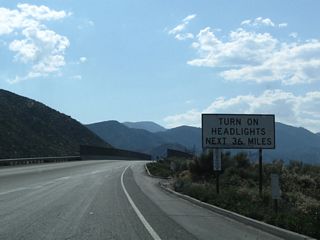 Leaving the Interstate 15 interchange, California 138 again travels uphill as it crosses over the Burlington Northern Santa Fe (BNSF) Railroad and approaches Mormon Rocks. For the next 36 miles of mostly two-lane, rural, state highway, motorists on California 138 must use headlights day and night.