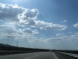 Shafts of late-day sunshine dominate the view along California 138 west. Along this section of road is a signalized intersection with Beekley Road, which travels north into Phelan.