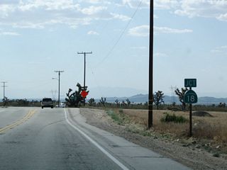 A California 18 route marker assembly is posted along California 138 west.