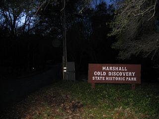 An entry sign for the Marshall Gold Discovery State Historic Park is posted near the entrance.