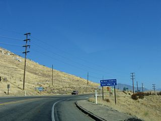 As a set of Southern California Edison power lines comes into view ahead of Barlow Road, which leads to Isabella Dam. Authorized in 1948 and completed in March 1953, Isabella Dam holds back water from the Kern River. This project was built to protect against downstream flooding, but it has ancillary uses for hydroelectric power and water supply for urban and agricultural use in the Central Valley. While California 155 passes by the main dam, a second dam closer to California 178 holds back water as part of the Borel project.
