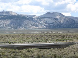 A nearby bridge visible from SR 158 carries southbound U.S. 395 traffic over Rush Creek, a major tributary of Mono Lake that flows northeast from Silver Lake through Grant Lake into Pumice Valley en route to Mono Lake. This arch bridge was built in 2001 per the date stamp in the center of the bridge.