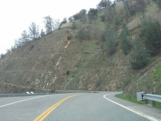 California 162 stays within sight of the waters of Lake Oroville as it proceeds north off the Bidwell Bar Bridge en route to the state route's eastern terminus. A realignment was required to prevent the highway from slipping into the lake, hence the deep cuts into the side of the hill.