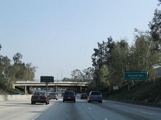 A roadside exit number sign is posted for Exit 9, Sherman Way.