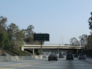 An older porcelain enamel sign for Sherman Way is posted in the median. Sherman Way is a major east-west arterial street.