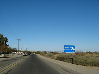 Welcome to California, the Golden State! The standard welcome sign featuring the state flower, the California Poppy, is located on the east side of the highway. On the west side of the highway is a recreational vehicle (RV) area.