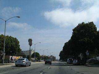 An urban street, Venice Boulevard proceeds through densely populated residential and commercial areas.