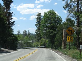 Passing above the Lake Arrowhead Village shopping center, SR 189 navigates through the first of several sharp curves along the course west to Blue Jay and Twin Peaks.