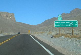 A mileage sign is posted on California 190 east near the eastern boundary of Death Valley National Park. Several of the original, button-copy, non-reflective signs had been replaced with reflective signs such as this one. Reflective signs first appeared in California in 1999, so this sign had been in place for only a short time at the time this picture was taken.