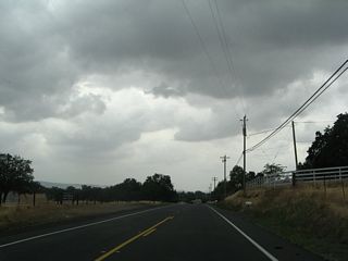 Reaching the bottom of the grade and passing through farms and ranches, California 191 sees some late spring storm clouds gathering on the horizon.