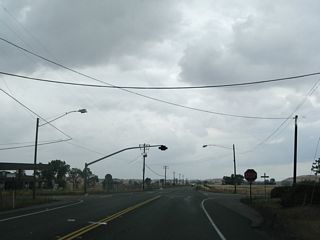 Southbound California 191 (Clark Road) approaches the four-way stop intersection with Durham-Pentz Road. Turn left (east) to Pentz and right (west) to California 99 and Durham.