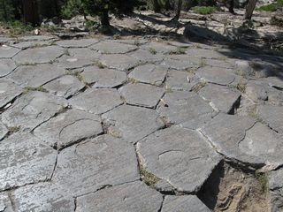 Near Rainbow Falls is Devils Postpile, which is also part of Devils Postpile National Monument. This area around the postpile is punctuated by the stack of volcanic columns that persist to this day in their orderly arrangement. The top of the pile is accessible, and the columns form a nearly smooth floor with mostly hexagonal-shaped tiles.