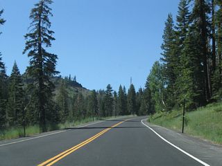 The state route retains two lanes even as the highway gains elevation. The parking lot for the mountain resort lies at the top of the hill.