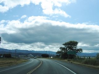 After crossing the Old River bridge, SR 221 curves northeast into the intersection with Goble Lane north and Waddington Street south.