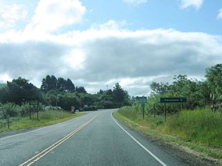 California 211 begins at Exit 692 from U.S. 101 by taking over Eel River Drive (which changes into Fernbridge Drive). Initially California 211 travels due south on Fernbridge Drive (Old U.S. 101) through the town of Fernbridge, then turns west to cross the Eel River. This mileage sign provides the distance to Ferndale, five miles.