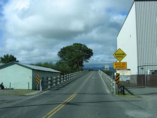 Upon turning at the stop sign, California 211 ascends across the Eel River. This bridge, built in 1911, is historical and features multiple concrete arches to carry the state highway across the massive river. Note the mileage for California 211 (78.56 miles), which includes quite a bit of the unconstructed state route south of Ferndale.