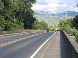 This view of the Russian River bridge looking east showcases the concrete guardrail and the scenic hills that surround the valley.