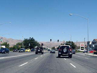After the Interstate 880 interchange, eastbound California 237 follows Calaveras Boulevard, which is a surface street with four to eight lanes of travel. Shopping centers are located on either side of the state route. Here, California 237 east approaches Abbott Avenue in Milpitas.