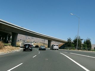 An on-ramp from McCarthy Boulevard joins California 237 east. A traffic signal ahead marks the end of the freeway. From here, California 237 will shift onto Calaveras Boulevard east.
