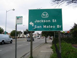 A trailblazer guide sign for California 92/Jackson Street west to the San Mateo-Hayward Bridge is posted on northbound California 238 prior to the left turn to Fletcher Lane. A trailblazer for California 92 is posted in the median.