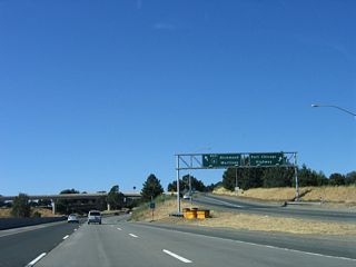 The exit ramp for Exit 3B, California 4 west splits with Port Chicago Highway immediately, and the ramp to California 4 west flies over California 242. Straight ahead, the three lanes continue to merge with California 4 east.