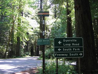 Approaching Dyerville Loop Road on southbound California 254 (Avenue of the Giants) near Founders Grove, a high water mark sign is posted for the extent of water during the 1964 floods. To U.S. 101 south, turn right at this intersection.
