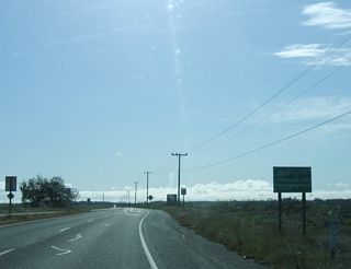 This mileage sign on southbound California 255 west provides the distance to Manila (three miles), Samoa (six miles), and Eureka (seven miles). The four-lane section comes to an end here.