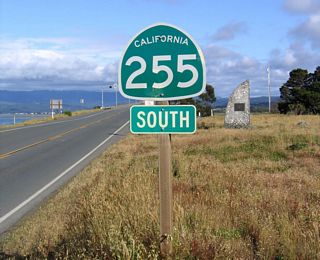 A second California 255 shield is posted as a reassurance marker on the approach to the Samoa Bridge. In the background is a monument identifying the date the bridge opened.