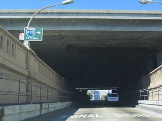 California 61/260 emerges from the tube, and a second sign advises travelers to Interstate 880 to prepare to make a right turn. Note the use of the button copy shield that was pasted over a California 17 shield, thus betraying the age of this sign.
