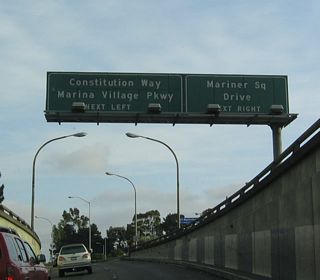 As California 260 emerges from the Webster Street Tube, the highway approaches an exit for Mariner Square Drive and Marina Village Parkway.