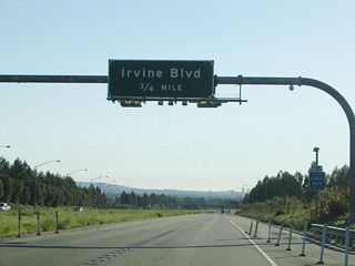 Over in the FasTrak lanes is an advance sign for Exit 2, Irvine Boulevard (0.75 mile). The cash lanes from the Irvine Ranch toll plaza will rejoin the main lanes ahead.