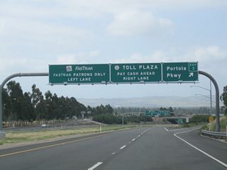 Southbound California 261 reaches Exit 3, Portola Parkway. Ahead, through traffic on California 261 approaches the Irvine Ranch Toll Plaza.