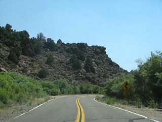 Amid the volcanic rock on either side of the highway, a warning sign advises that the next ten miles of highway are winding with curves. This is not a high-speed highway similar to U.S. 395.