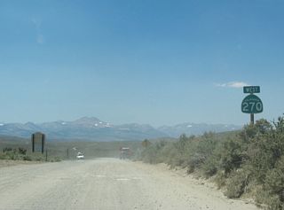 The first westbound California 270 reassurance shield assembly is posted on the gravel segment just prior to the transition onto a paved surface.