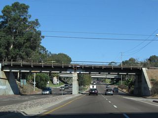 As traffic from northbound Interstate 5 merges onto eastbound Balboa Avenue on the right, Balboa Avenue passes under the San Diego Northern Railway and the Blue Line.
