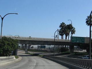 Queens Way south lowers to run alongside Harbor Scenic Drive south to the Queen Mary and Cruise Ship Terminal.