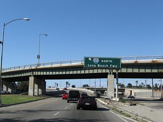The freeway turns northwest to cross over the Los Angeles River via the Shoemaker Bridge to connect with Interstate 710 (Long Beach Freeway) north toward Pasadena.