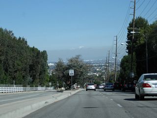 Snow capped peaks rise in the distance as Crenshaw Boulevard lowers from north slope of the hills.