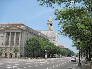 Eight lanes of Pennsylvania Avenue NW at the intersection with 10th Street NW at the Internal Revenue Service Building. The Old Post Office Pavilion rises beyond the IRS Building.