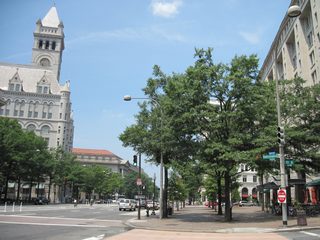 Eight lanes of Pennsylvania Avenue NW at the intersection with 10th Street NW at the Internal Revenue Service Building. The Old Post Office Pavilion rises beyond the IRS Building.