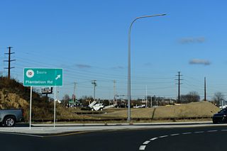 SR 1D curves southeast from the roundabout with Belltown Road along Plantation Road.