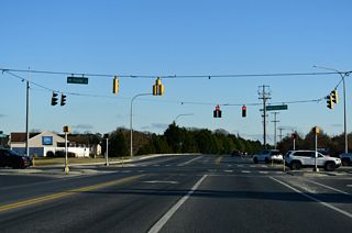 Both inventoried as Reference Road 283, Cedar Grove Road east and Postal Lane west come together at a signalized intersection with SR 1D (Plantation Road).