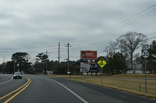Curving southward toward Millsboro, SR 24 Business (John J. Williams Highway) next meets the south end of SR 30 (Gravel Hill Road).